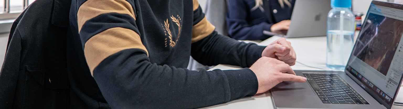 Person working on a laptop, reviewing design files in an office setting