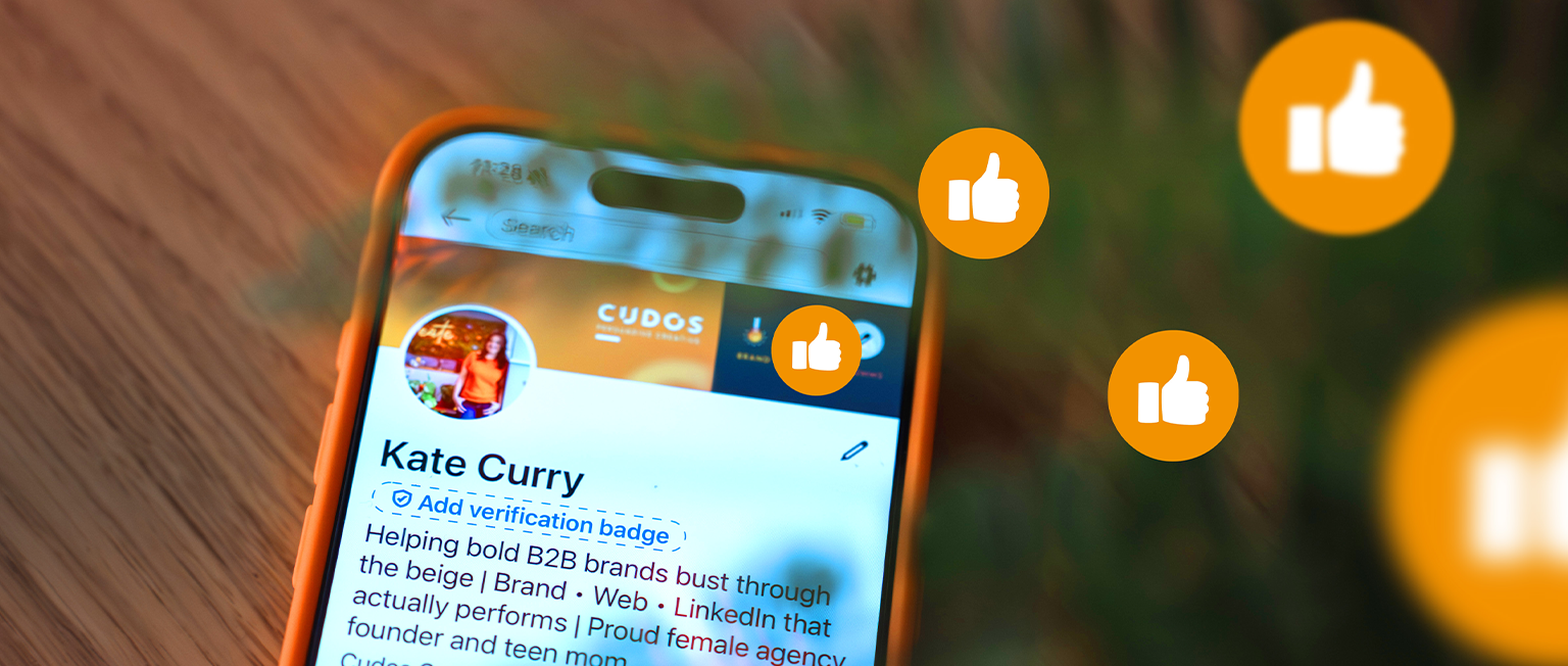 LinkedIn profile on a smartphone screen with engagement icons, illustrating how showing personality and authenticity on LinkedIn can increase visibility, engagement and business opportunities for B2B professionals.